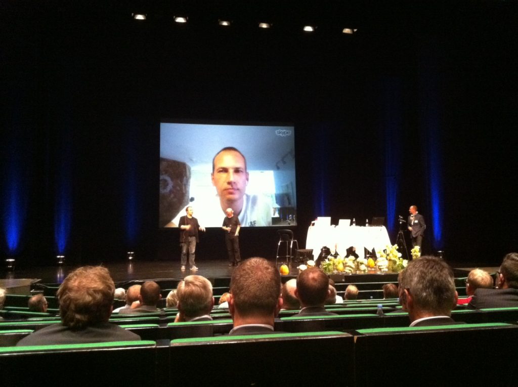 Martin Thorborg p&aring; en storsk&aelig;rm via Skype foran publikum i en foredragssal.