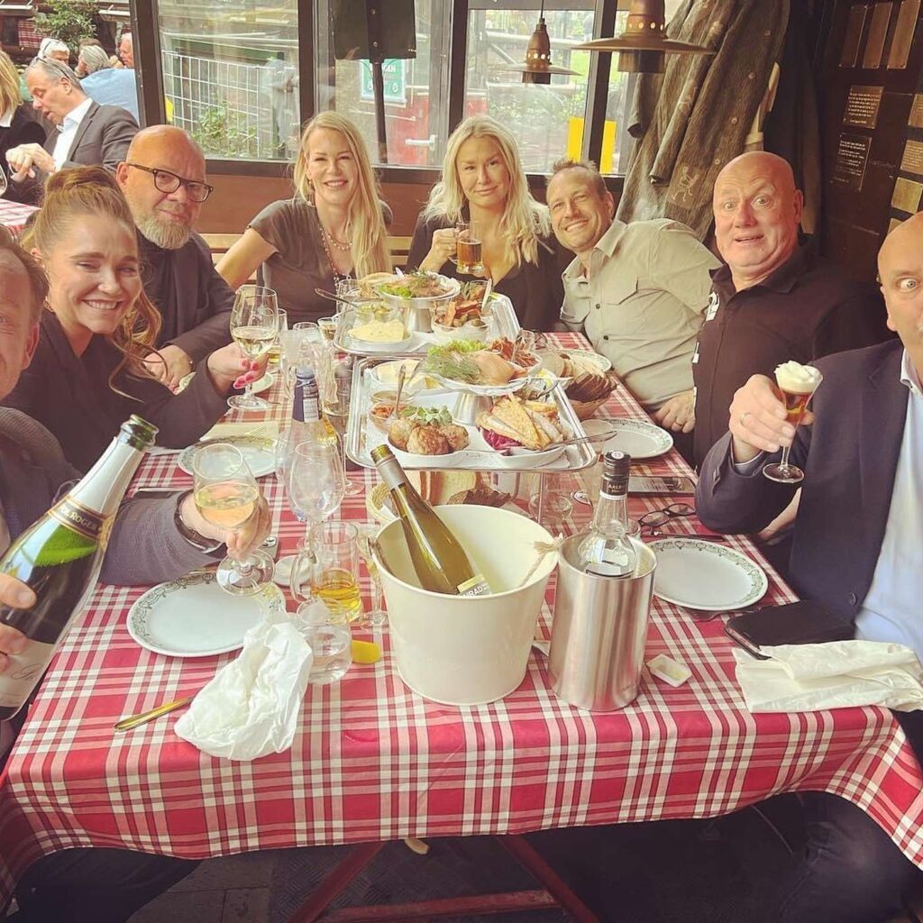 En gruppe mennesker ved et dækket bord med en rødternet dug.