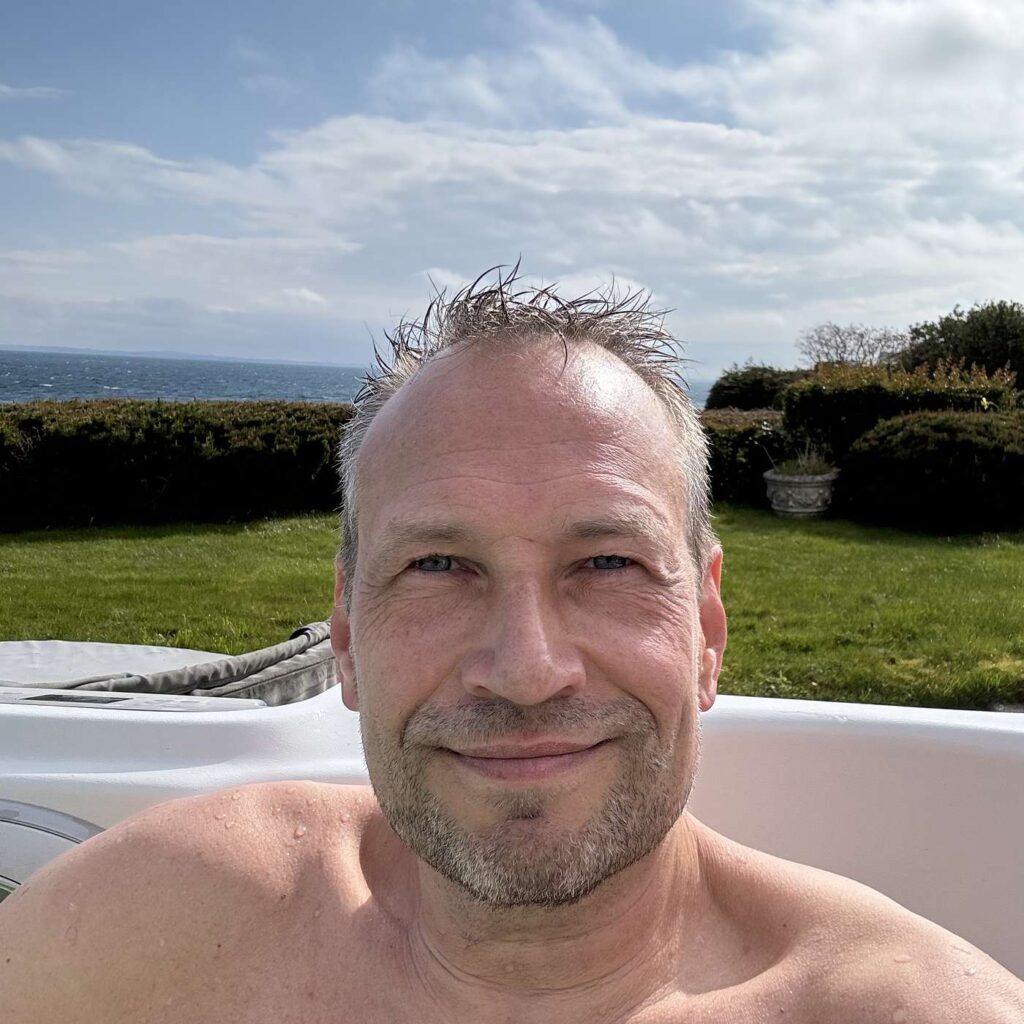 Martin Thorborg udendørs med have og landskab i baggrunden.
