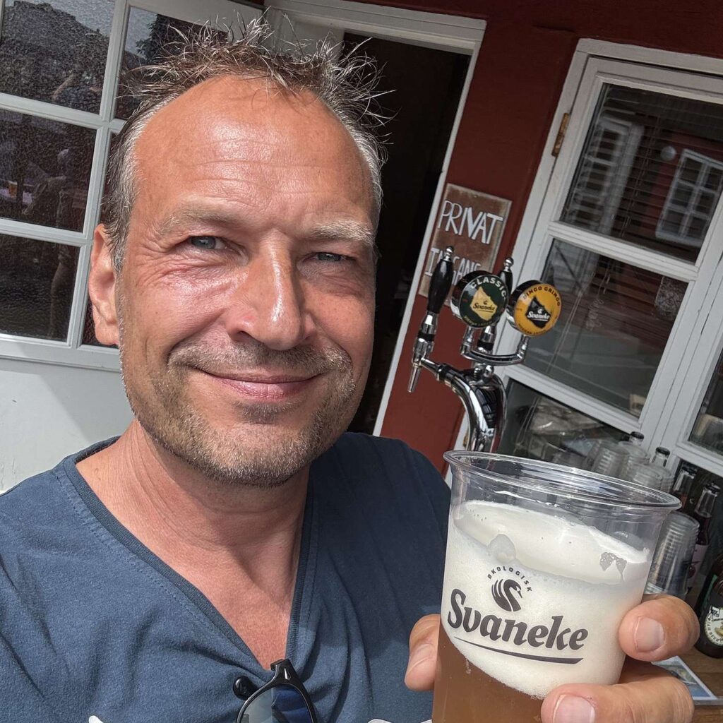 Martin Thorborg med et &oslash;lglas foran en indgang.