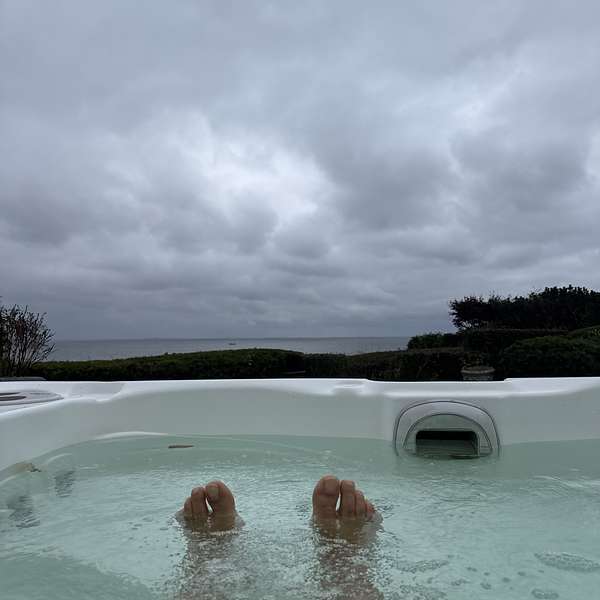Bare f&oslash;dder i en udend&oslash;rs jacuzzi under en overskyet himmel.