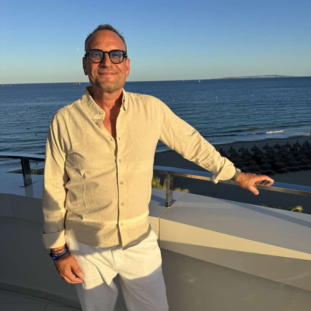 Martin Thorborg med solbriller ved en r&aelig;ling med havet i baggrunden.