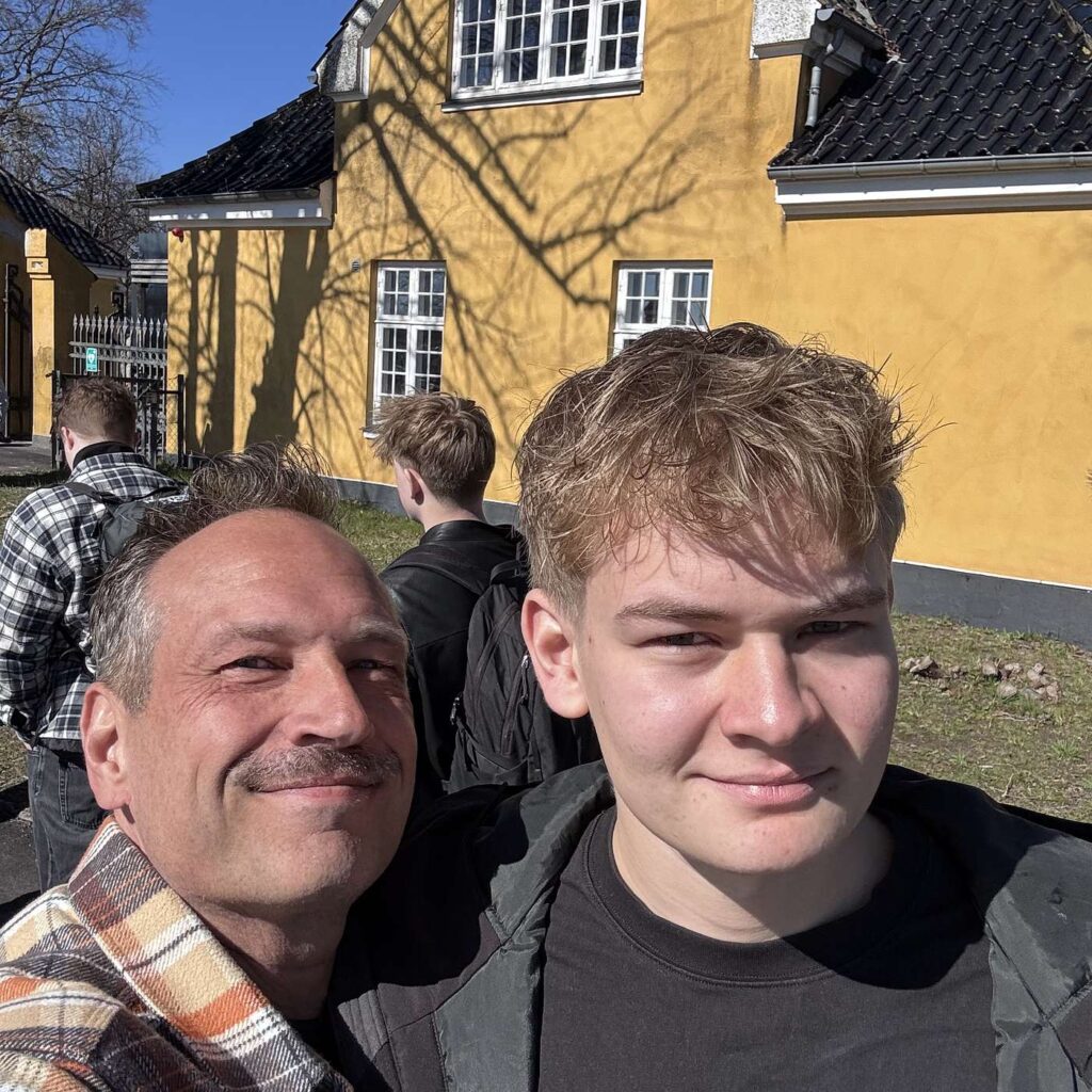 Martin Thorborg sammen med sin s&oslash;n Mads foran en gul bygning.