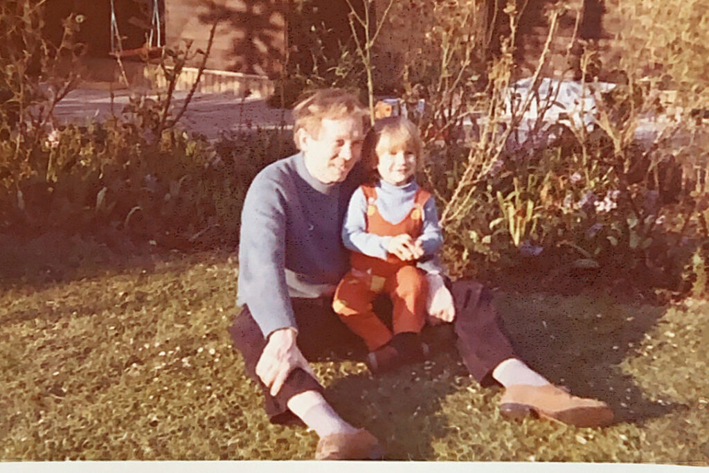 Et gammelt familiefoto af en voksen og et barn i en have.